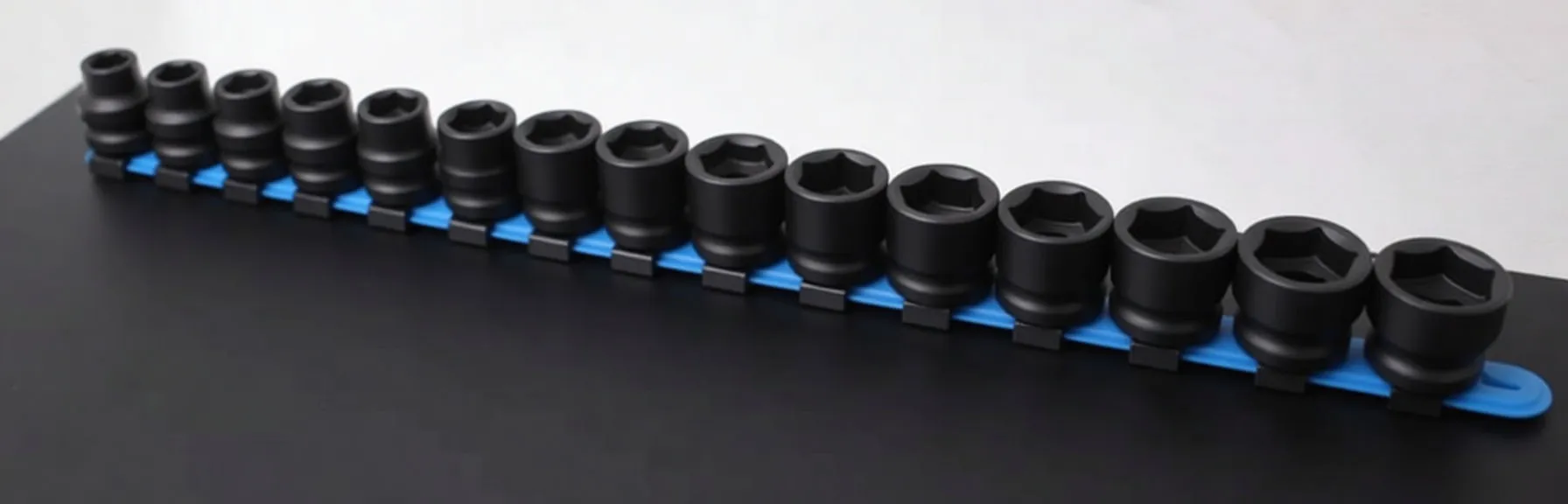 Row of black impact sockets on blue mounting rail, close view of socket faces with ASTA branding and size markings.