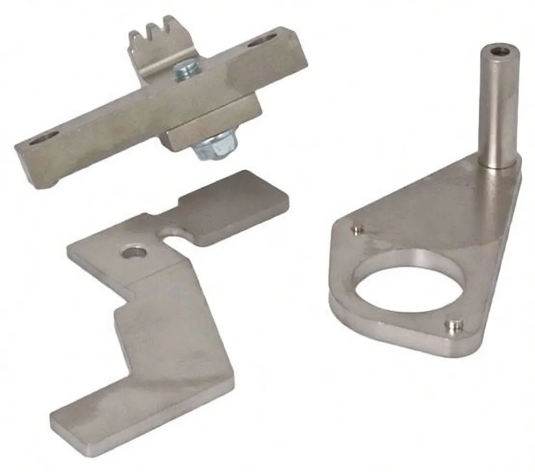 Close-up of stainless-looking timing tools: a bracket with a round hole and pin stamped 'SaTra S-XLR20', serrated and L-shaped locator plates, and a bolted rectangular piece.