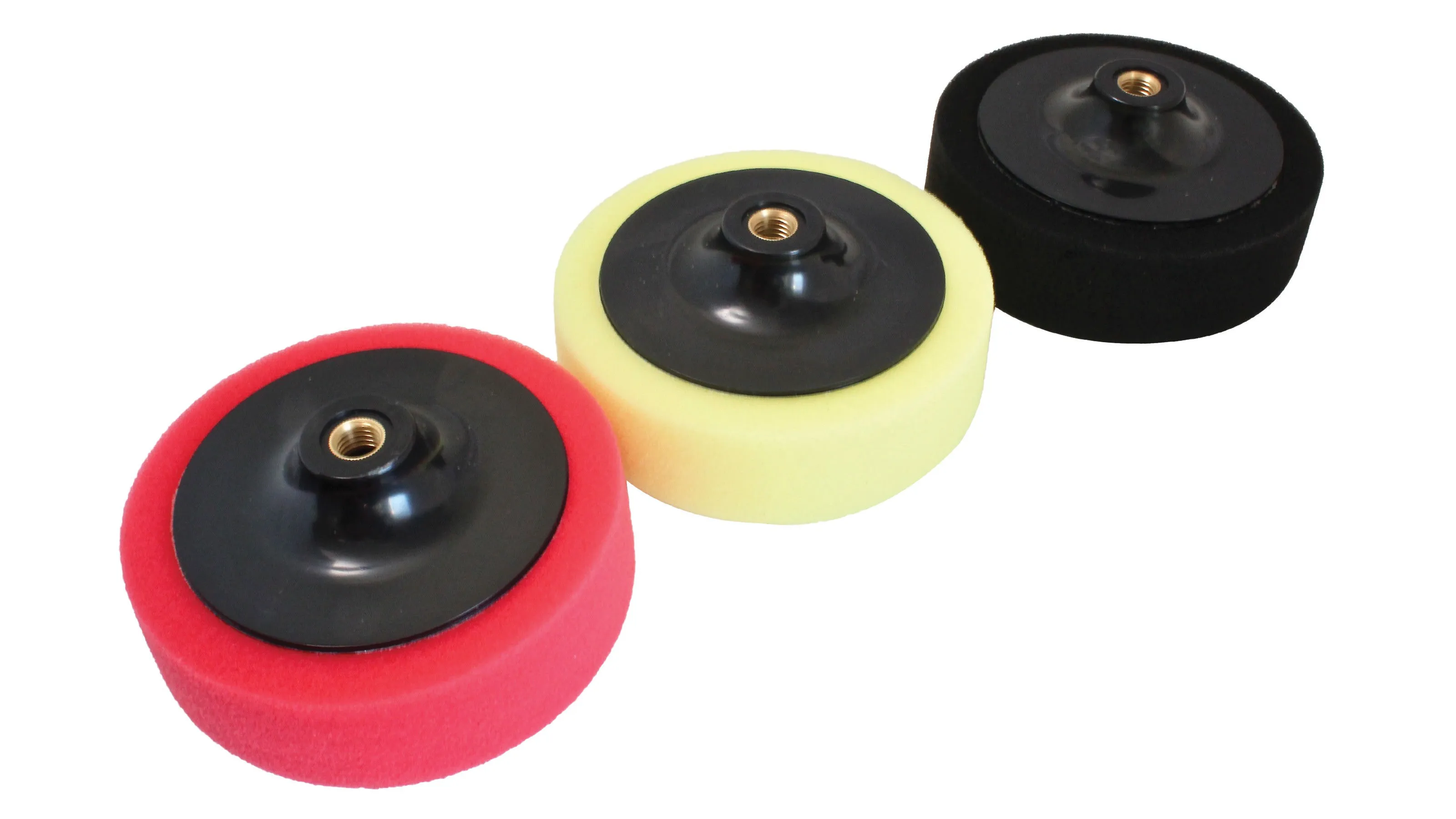 Angled view of three foam polishing pads in a row showing thickness and central threaded backing