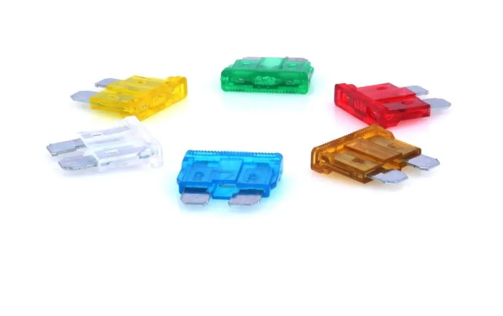 Low-angle close-up of multiple colored automotive blade fuses showing metal blades and internal fuse elements