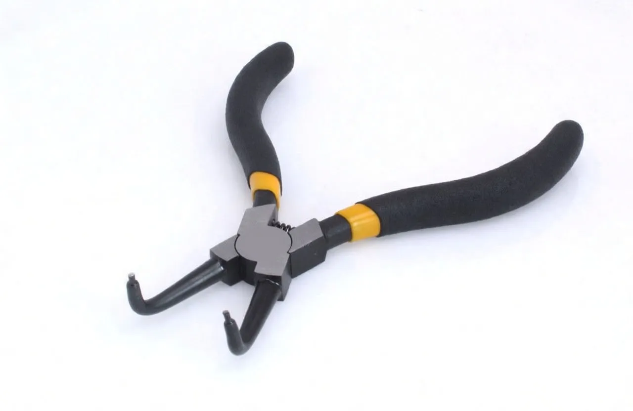 Angled close-up of seger pliers showing stamped logo on pivot, bent jaws with pin tips, spring and textured handles