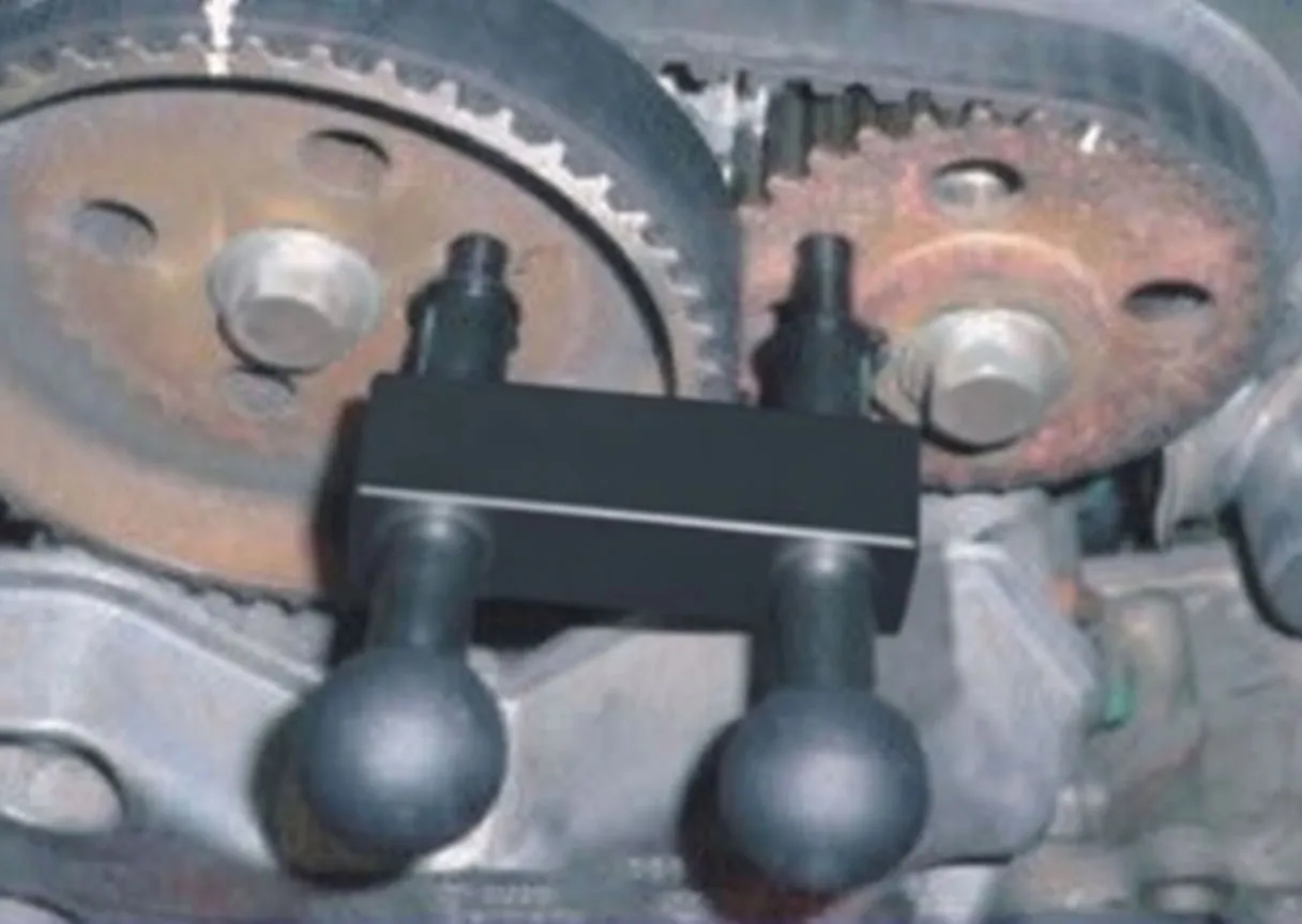 Camshaft alignment tool fitted across two camshaft sprockets on an engine, pins inserted into the sprocket holes to lock timing