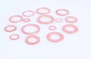 A few flat, circular copper washers with central holes laid on a pale surface, showing their smooth, reddish-metallic finish and varying small diameters.