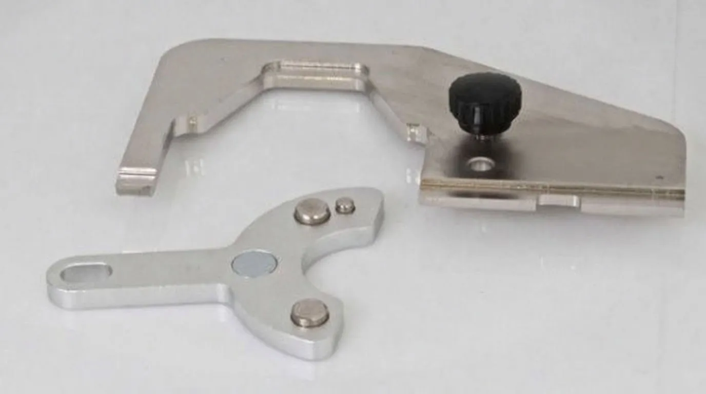 Stainless-steel U-shaped fork and clamping plate with black thumbscrew, plus a small three-armed silver adaptor.