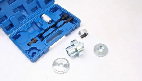 Blue case open with several bush puller parts laid out on white background — discs, central adapter, bearing and rods