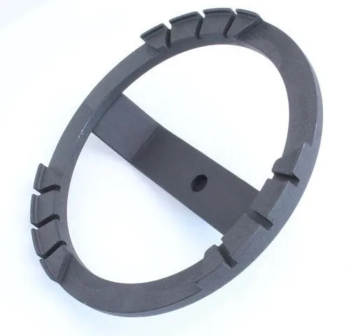 Oblique close-up of cast metal ring tool with engagement lugs and central arm with through-hole