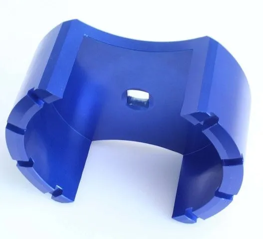 Angled underside of blue anodized fuel tank lid removal tool showing slots and square drive recess