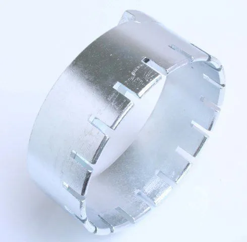 Side/angled view of a round notched metal ring tool with internal rectangular slots and a flat bridging bar.