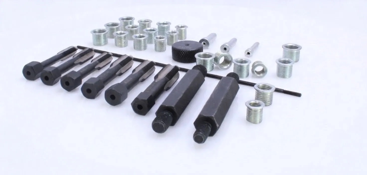 Laid-out re-threading kit parts: black taps and drivers, knurled installer, guide rod and many silver threaded inserts