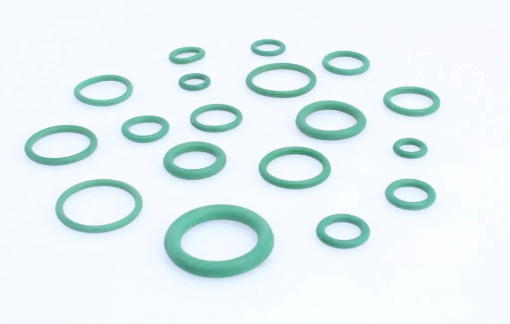 Closeup of assorted green O‑rings of different sizes laid out on a white surface.