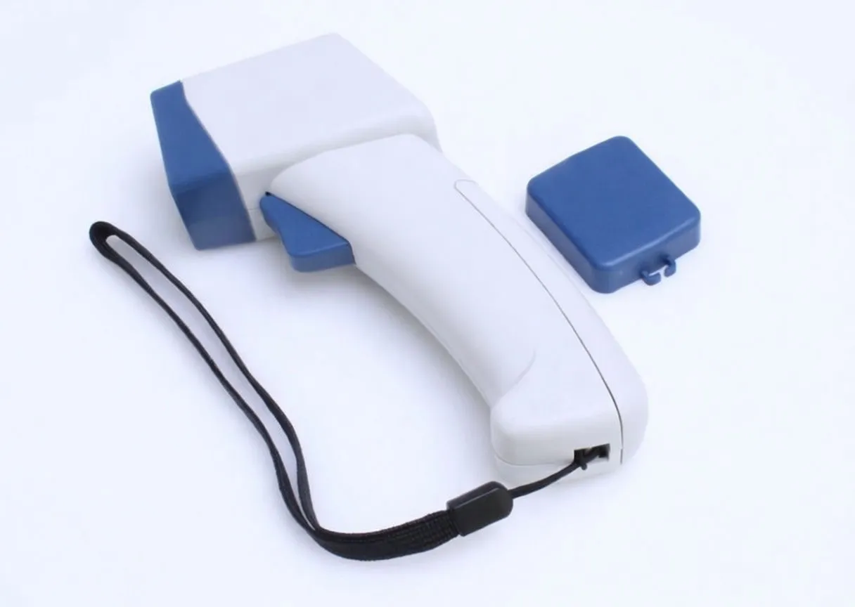 Side view of white and blue laser pyrometer on a surface with protective cap removed and yellow caution label visible