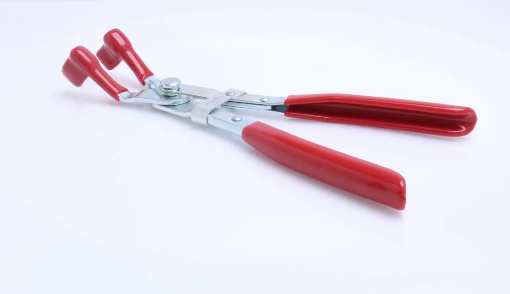 Low-angle view of pliers on a white surface, showing red handles, red hooked jaw tips and silver pivot/hinge assembly.