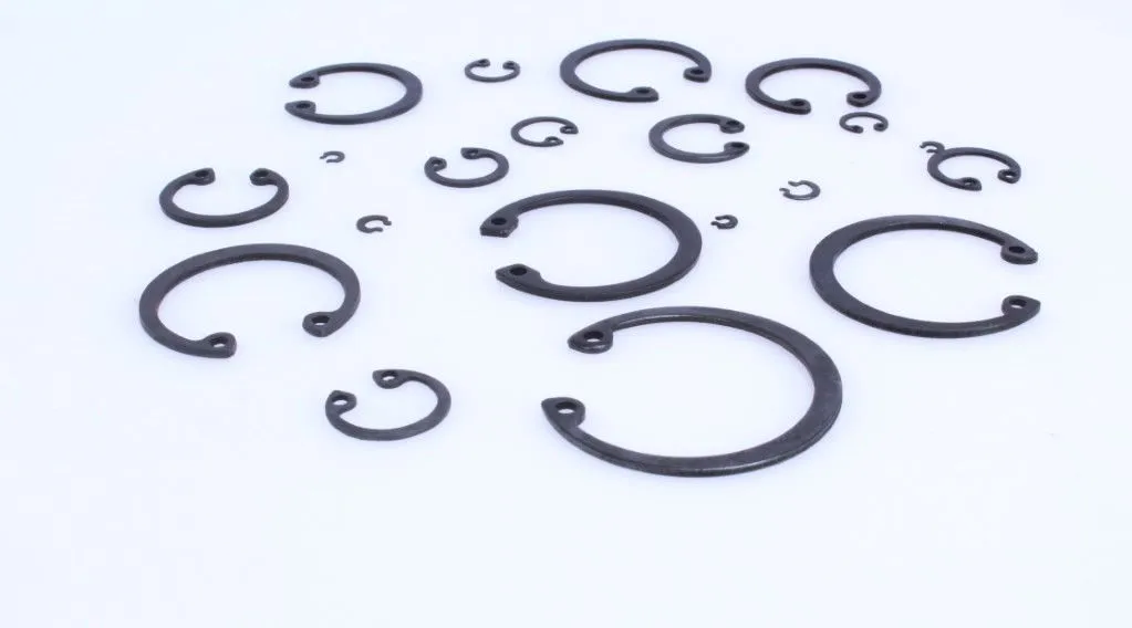 Assorted black internal circlips laid out on white background showing different diameters and plier holes