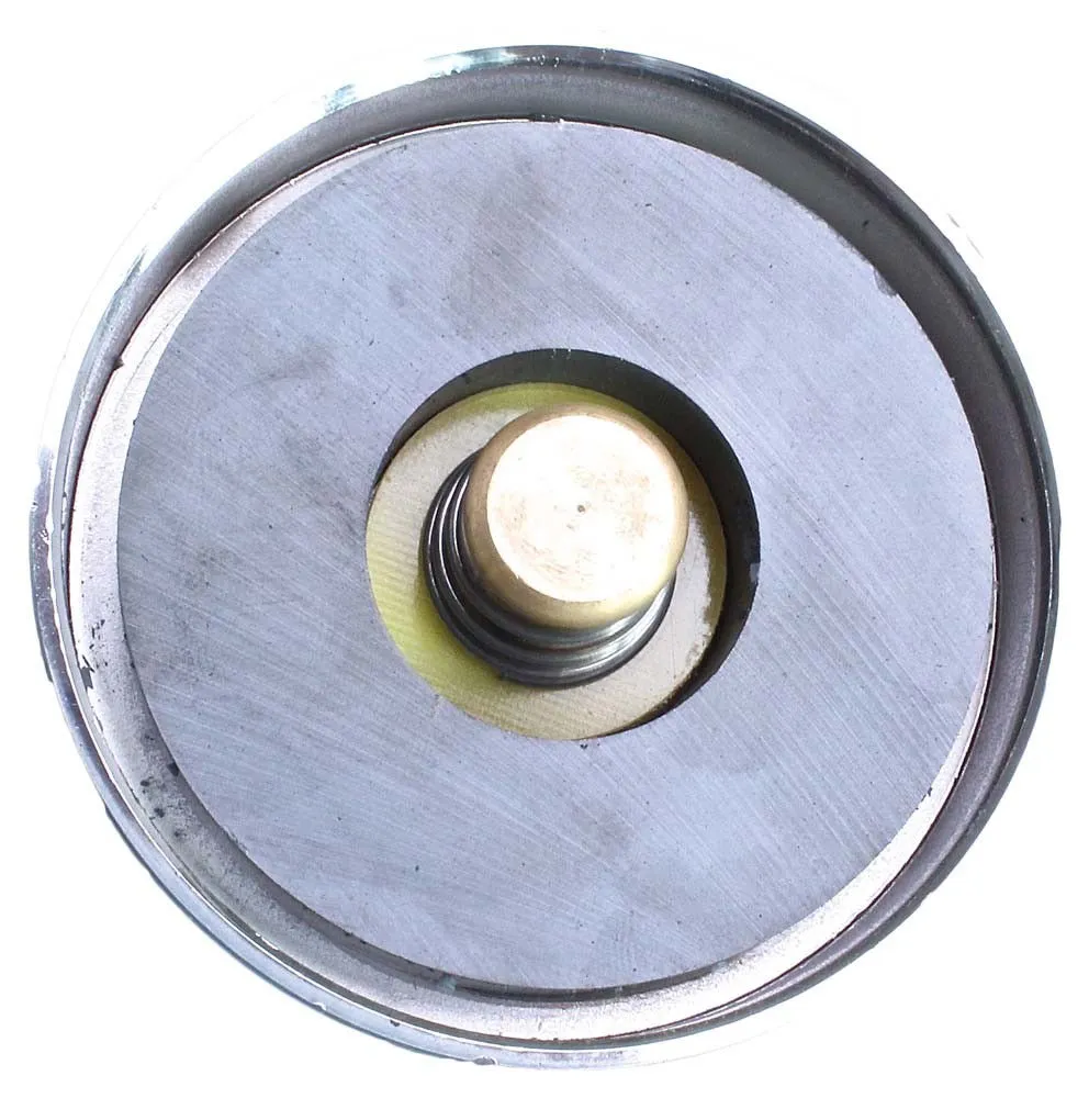 Rear view of round magnet showing dark magnet disc, central spring and brass plunger inside a steel cup rim.