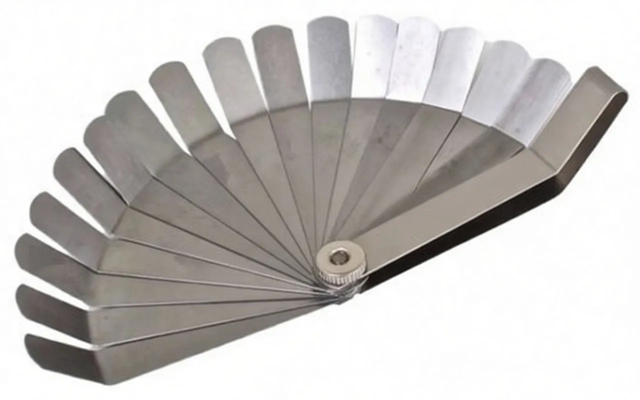 Feeler gauge set fanned out on a white surface showing blade markings and the central pivot, stainless steel construction.