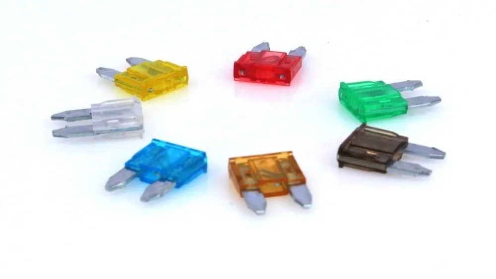 Mini automotive fuses in multiple translucent colors arranged in a circle, showing metal blades and internal fuse elements.
