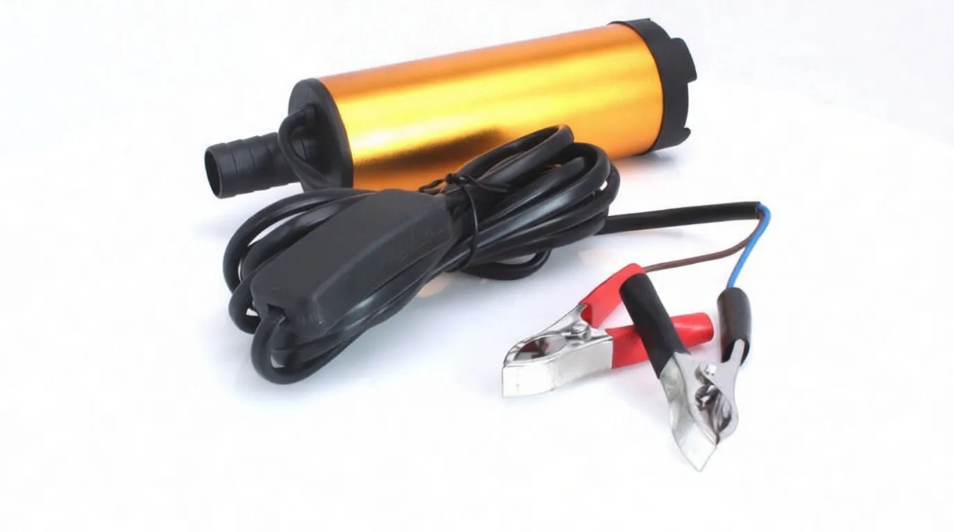 Angled shot of an orange mini diesel pump with brand text, outlet spout, coiled power cord and inline switch, plus red and black battery clips.