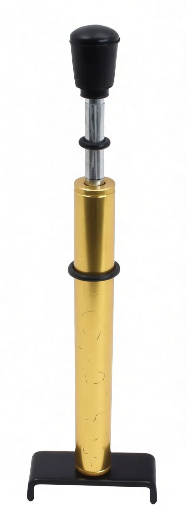 Vertical front view of gold belt tension gauge on black U-shaped base with visible scale, arrow, O-rings and rubber-tipped plunger