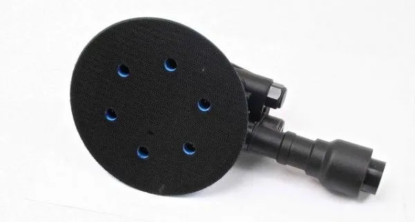 Bottom of orbital sander showing black hook-and-loop pad with six dust extraction holes and rear hose adapter