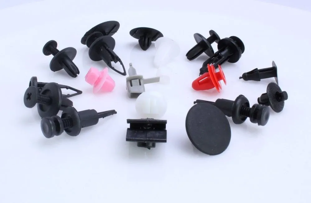 Assortment of individual plastic trim clips and push rivets in black, white, pink and red on white background