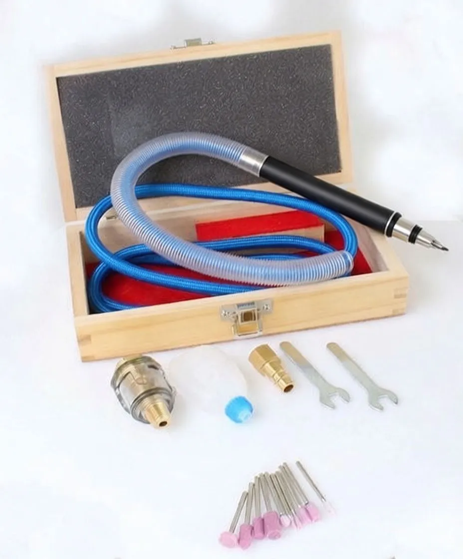 Pneumatic handpiece and accessories next to a wooden box: connectors, oil bottle, wrenches, and pink grinding bits
