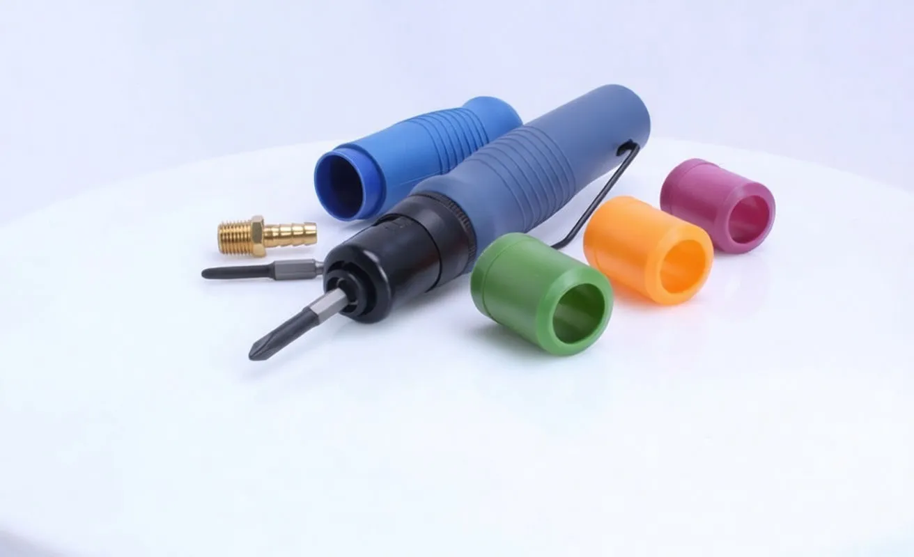 Pneumatic screwdriver with spare bit, brass fitting and colorful plastic caps on white surface