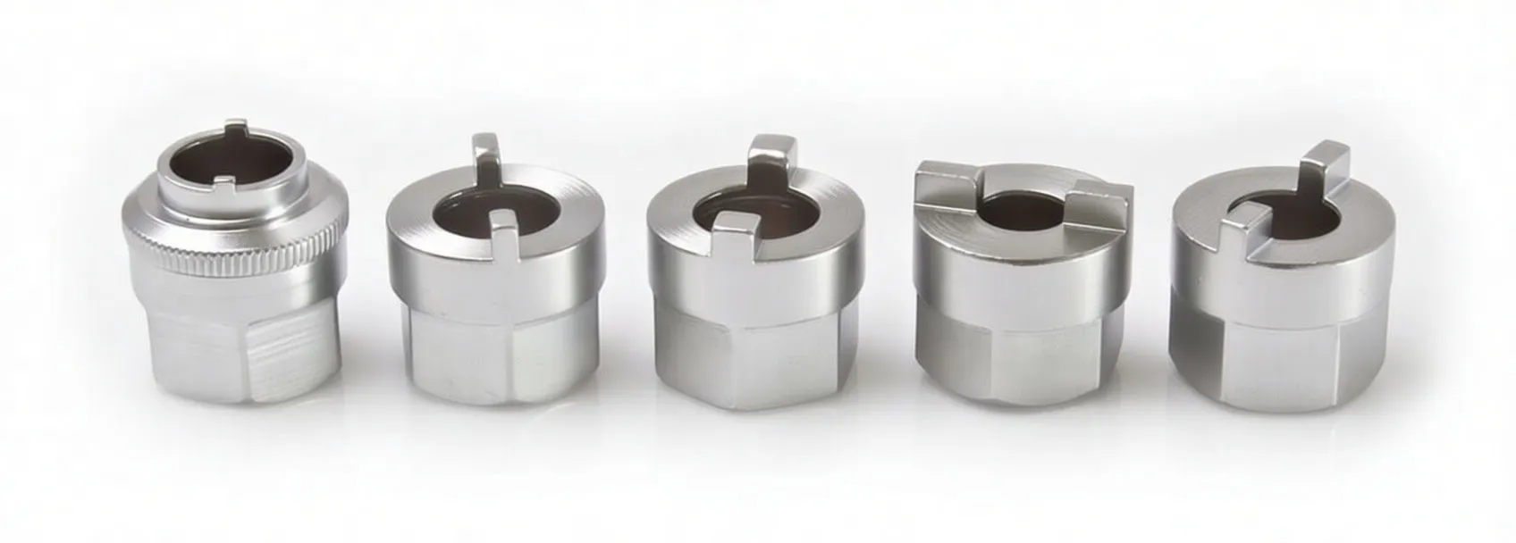 Angled view of five silver cast inserts for shock absorber bolts with top slots, flat outer faces and size markings.