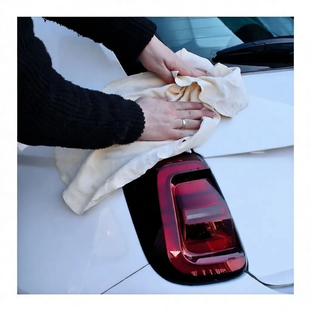 Person using chamois to dry or polish car hood and headlight
