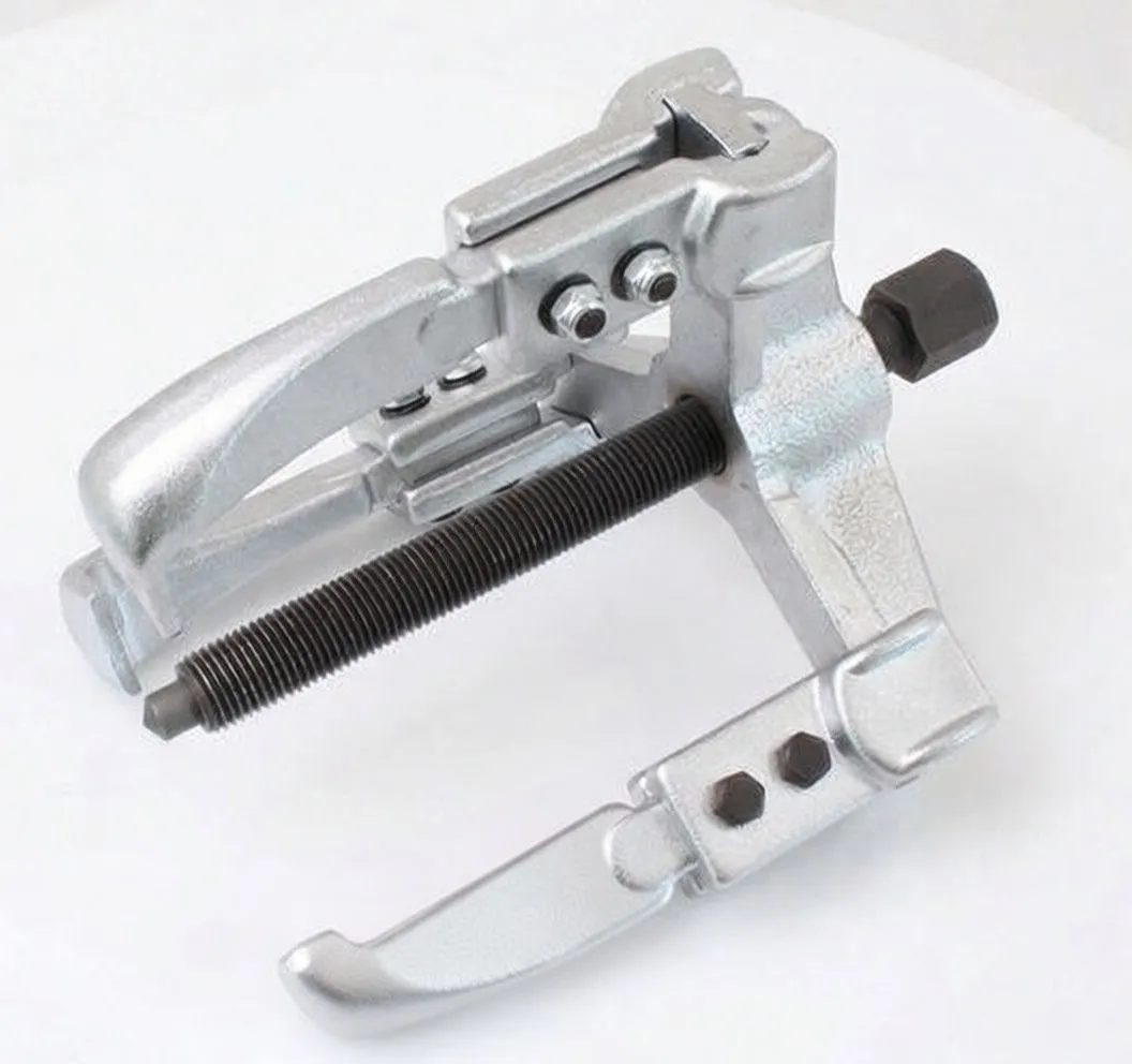 Close-up of three-arm puller showing threaded rod, hex head, pivot bolts, and printed logo on arm