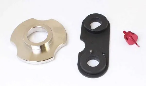 Silver adapter, black link plate with dowel, and small red locating pin on white background