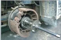 Bearing extractor mounted on a truck axle hub with backing plate and brake shoes visible