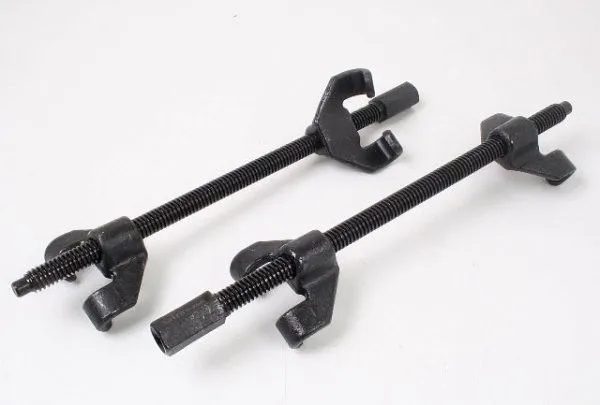 Close-up of two black universal spring compressor clamps showing threaded rods, U-shaped jaws and hex driver ends