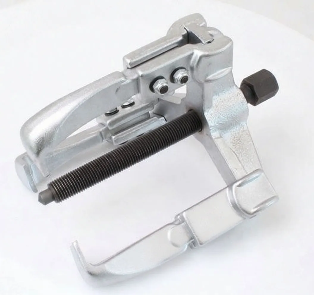 close-up view of three-arm puller showing threaded screw, cast yoke, pivot bolts and hooked arms